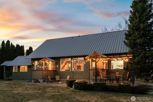 back of house at dusk featuring metal roof, a patio area, and a standing seam roof