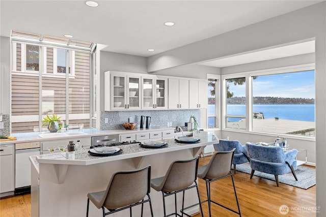 kitchen featuring light countertops, backsplash, light wood-style flooring, white cabinets, and a kitchen breakfast bar