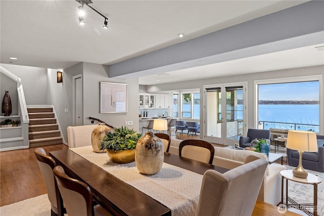 dining area with recessed lighting, a water view, light wood-style flooring, and stairs