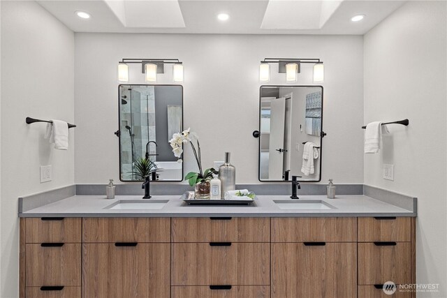 full bathroom with double vanity, a stall shower, a skylight, and a sink