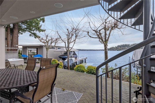 balcony with outdoor dining space, a boat dock, and a water view