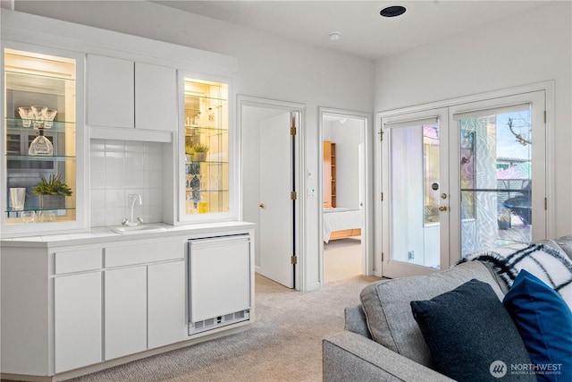 interior space with access to exterior, french doors, light colored carpet, ensuite bathroom, and a sink