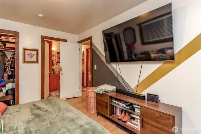 bedroom featuring a walk in closet, a closet, and light wood finished floors