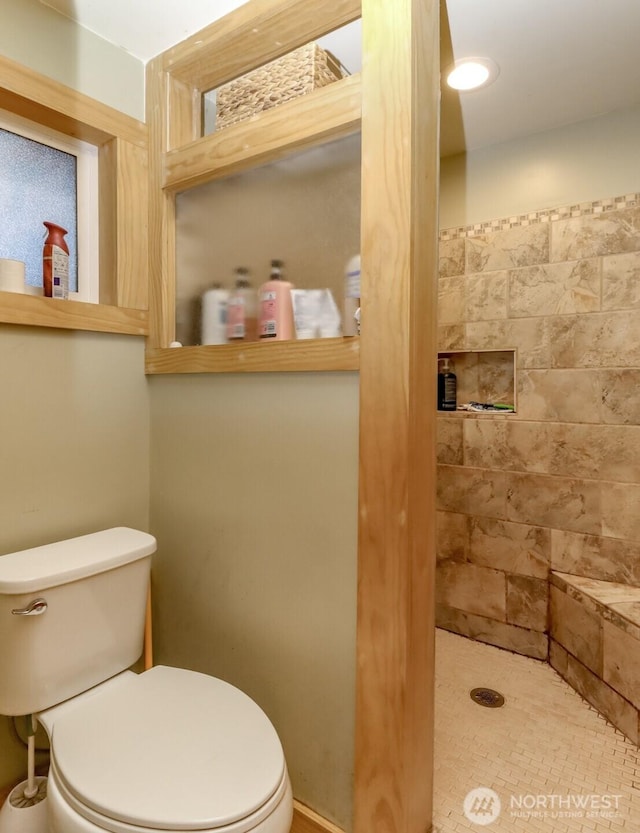 full bath with tiled shower and toilet