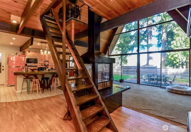 stairway featuring recessed lighting, lofted ceiling with beams, expansive windows, wood finished floors, and wooden ceiling