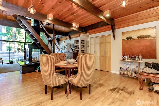 dining space featuring stairs, beam ceiling, wooden ceiling, and wood finished floors