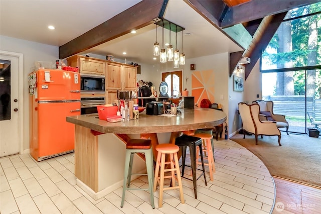 kitchen featuring freestanding refrigerator, light brown cabinets, black microwave, oven, and beamed ceiling