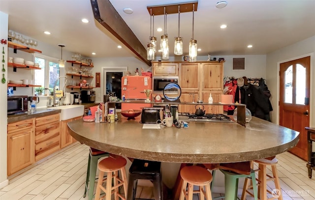 kitchen with appliances with stainless steel finishes, a breakfast bar, a large island with sink, open shelves, and recessed lighting