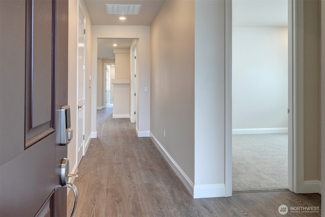 hallway featuring dark wood-type flooring, visible vents, and baseboards