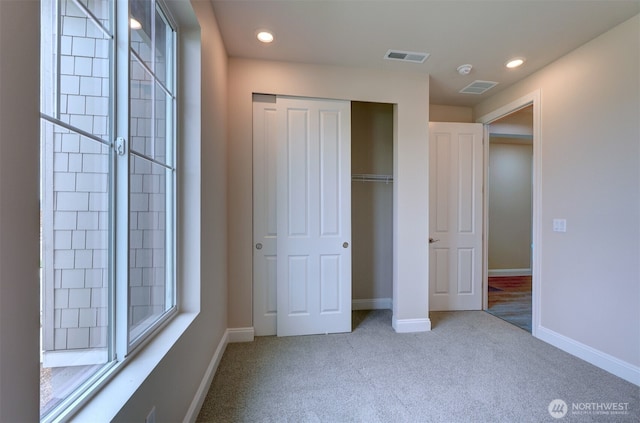 unfurnished bedroom with a closet, carpet, visible vents, and baseboards