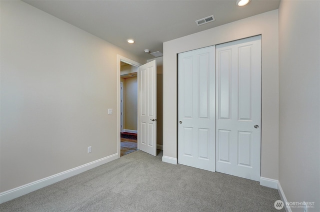 unfurnished bedroom with carpet floors, baseboards, visible vents, and a closet