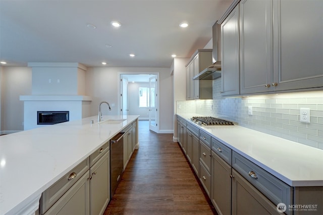 kitchen with dark wood finished floors, stainless steel gas cooktop, light countertops, decorative backsplash, and a sink