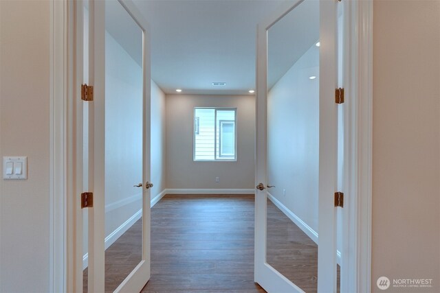 hallway featuring visible vents, baseboards, and wood finished floors