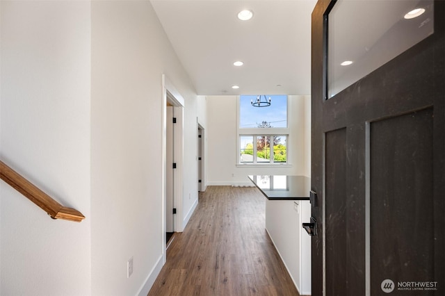 hallway with baseboards, wood finished floors, and recessed lighting