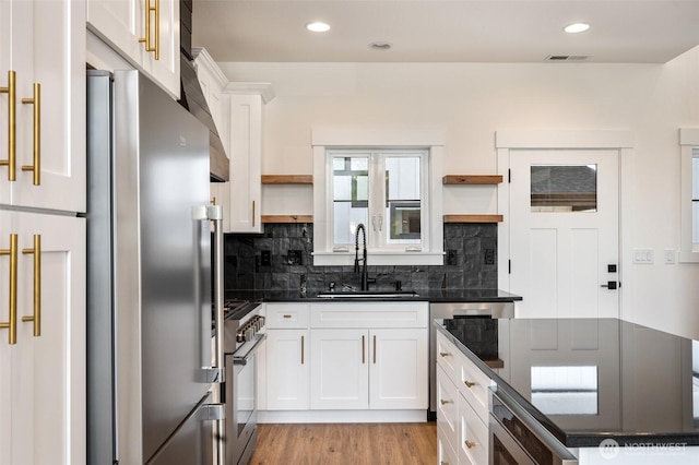 kitchen with appliances with stainless steel finishes, a sink, backsplash, and open shelves