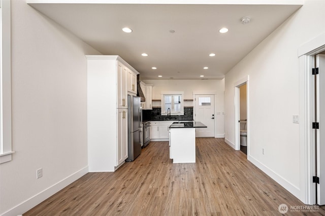 kitchen featuring tasteful backsplash, light wood-style flooring, freestanding refrigerator, and white cabinets