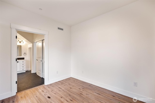 empty room with visible vents, baseboards, and wood finished floors