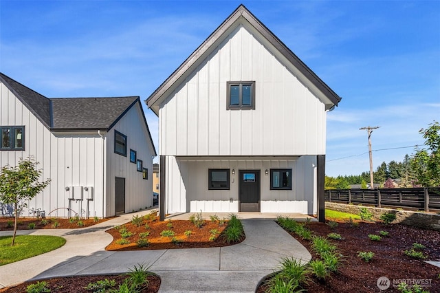 modern inspired farmhouse with board and batten siding, covered porch, roof with shingles, and fence