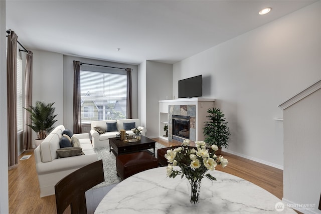 living area with a fireplace, baseboards, wood finished floors, and recessed lighting