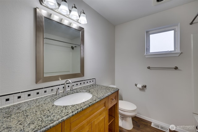 full bath with visible vents, toilet, vanity, baseboards, and walk in shower