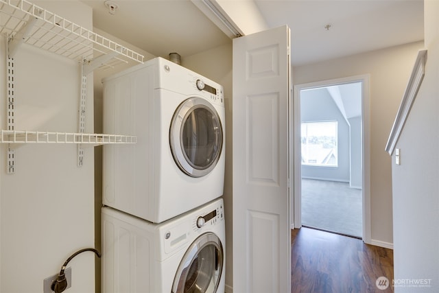 clothes washing area featuring laundry area, baseboards, dark wood-style floors, and stacked washer / drying machine