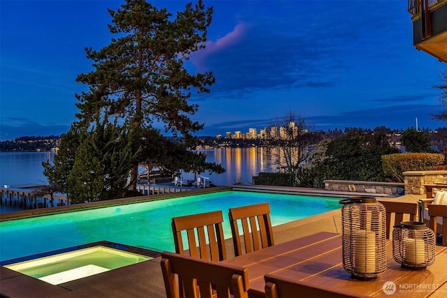 pool with an in ground hot tub, a patio area, and a water view