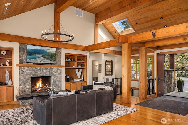 living area featuring a stone fireplace, wood finished floors, an inviting chandelier, and built in features