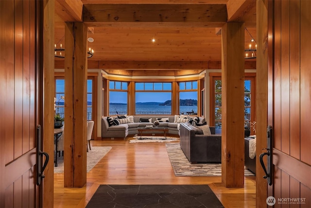 entrance foyer featuring a water view, wooden walls, and wood finished floors