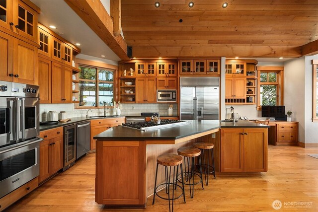 kitchen with dark countertops, open shelves, built in appliances, brown cabinets, and a sink