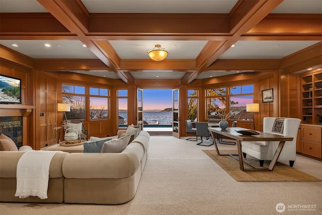 carpeted living room with built in shelves, coffered ceiling, a tile fireplace, wood walls, and beamed ceiling