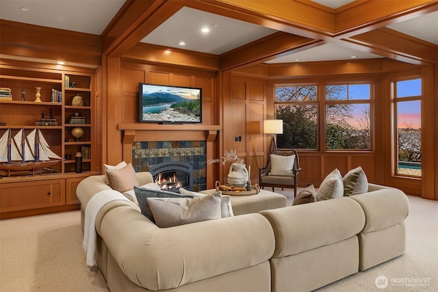 sitting room featuring built in shelves, coffered ceiling, carpet floors, beam ceiling, and a lit fireplace