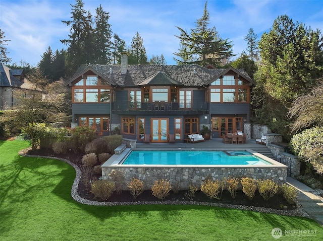 back of property with a lawn, french doors, a chimney, an outdoor pool, and a patio