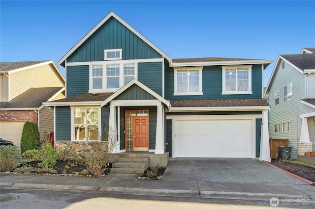 view of front of home with driveway, an attached garage, a shingled roof, and board and batten siding