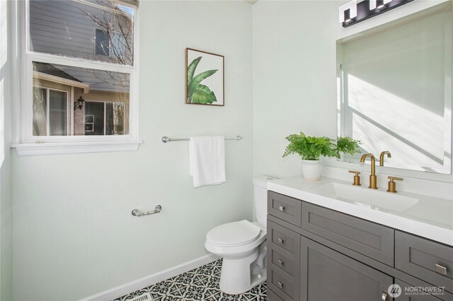 bathroom with plenty of natural light, vanity, toilet, and baseboards