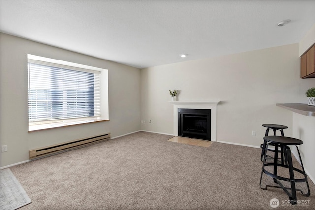 unfurnished living room with carpet floors, a fireplace with flush hearth, a baseboard heating unit, and baseboards