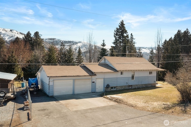 ranch-style home with driveway, an attached garage, a mountain view, and a front yard