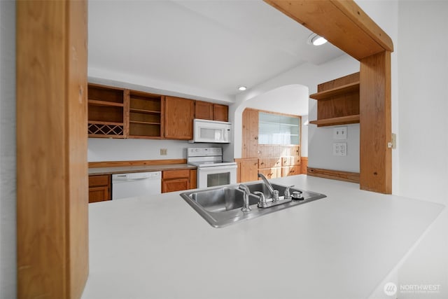 kitchen featuring white appliances, brown cabinets, a sink, and open shelves