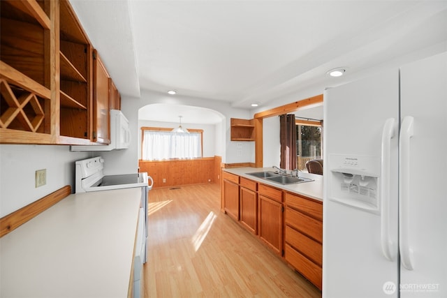 kitchen featuring arched walkways, open shelves, a sink, light wood-type flooring, and white appliances