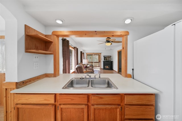 kitchen featuring a ceiling fan, open floor plan, light countertops, open shelves, and a sink