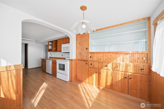 kitchen with light wood-style floors, arched walkways, white appliances, and open shelves