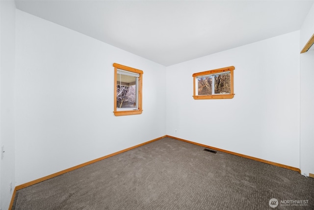 empty room featuring carpet, visible vents, and baseboards