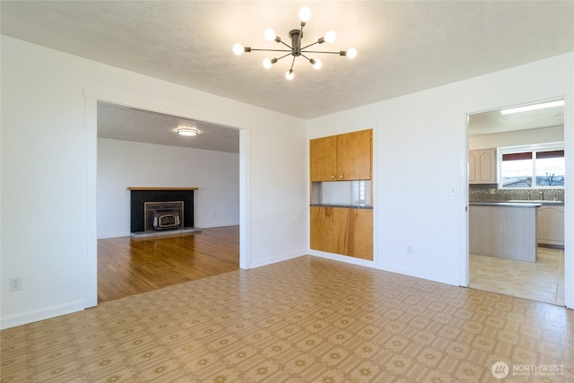 unfurnished living room featuring a sink, baseboards, a notable chandelier, and light floors