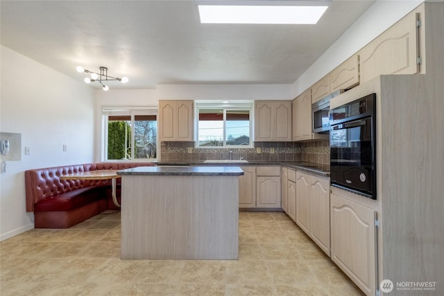 kitchen with black appliances, a sink, backsplash, dark countertops, and a center island