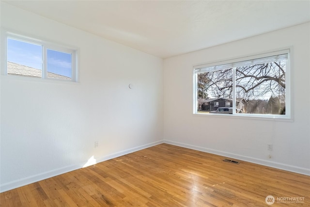 empty room with visible vents, baseboards, and light wood finished floors