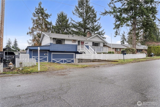 view of front of house with a garage, a chimney, and fence