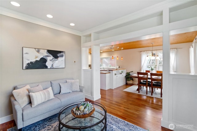 living room featuring recessed lighting, baseboards, ornamental molding, and wood finished floors