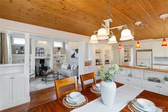 dining area featuring visible vents, built in shelves, dark wood-style floors, wooden ceiling, and a wood stove