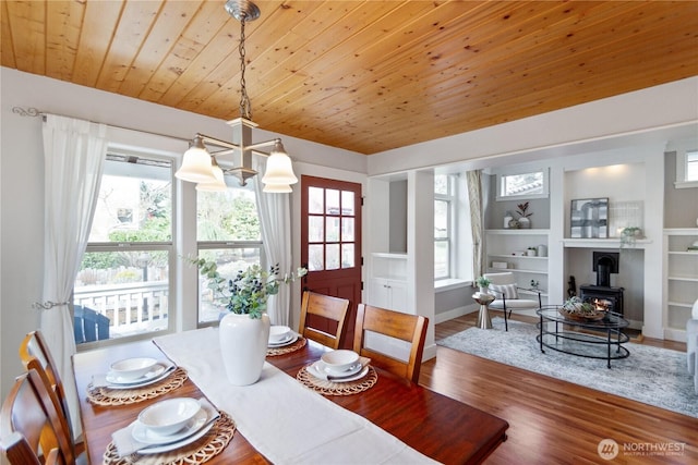 dining area with wooden ceiling, a wood stove, wood finished floors, and a wealth of natural light