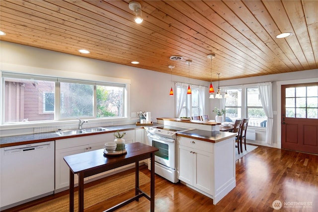 kitchen with white appliances, wood finished floors, a peninsula, a sink, and white cabinets