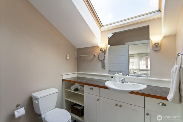 bathroom with vanity, lofted ceiling with skylight, and toilet